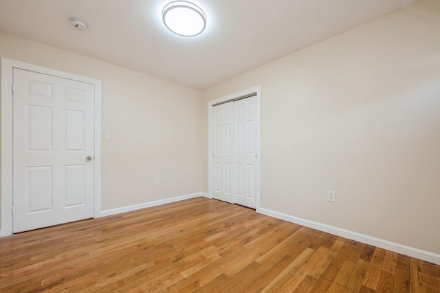 unfurnished bedroom with a closet, light wood-style flooring, and baseboards