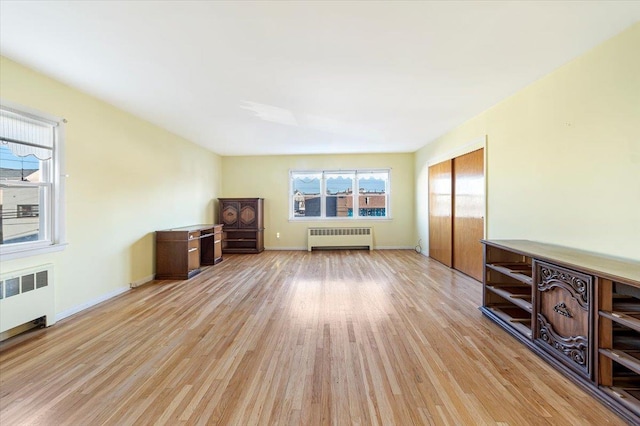 unfurnished living room with baseboards, radiator heating unit, and light wood-style floors