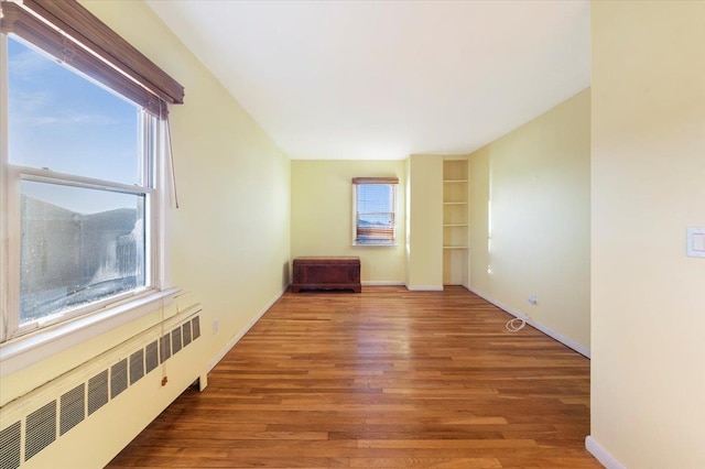 spare room with radiator, wood finished floors, and baseboards