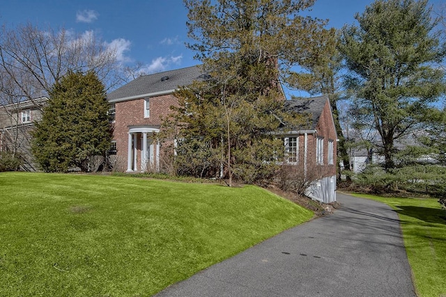 view of home's exterior with brick siding, a lawn, driveway, and an attached garage