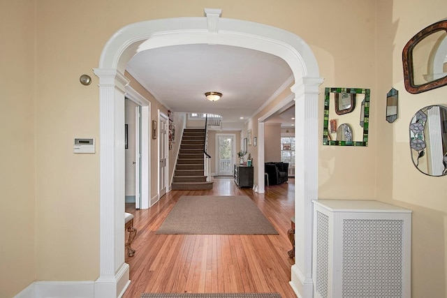 entrance foyer featuring arched walkways, stairway, ornate columns, and wood finished floors