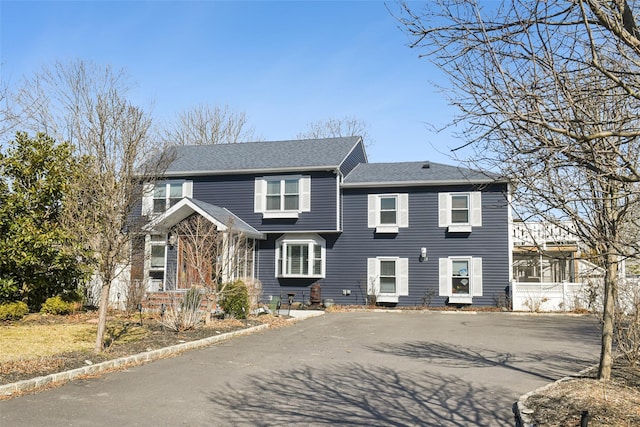 traditional-style home featuring driveway and roof with shingles