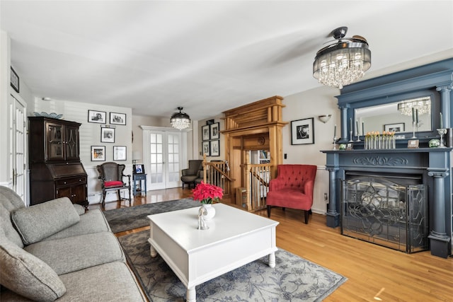 living room featuring a chandelier, french doors, a fireplace, and wood finished floors