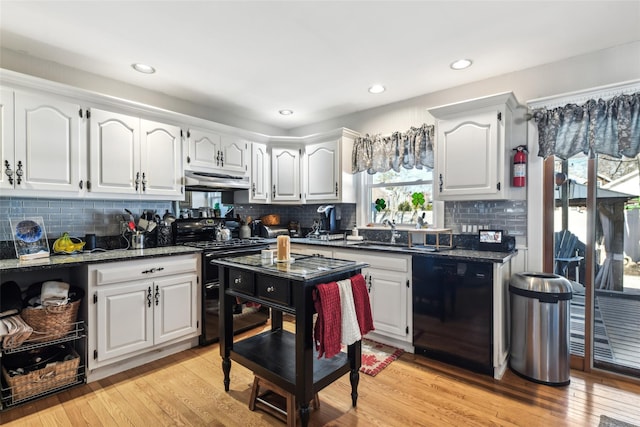 kitchen featuring under cabinet range hood, light wood-style flooring, white cabinets, black appliances, and a sink