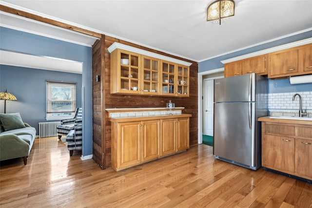 kitchen featuring ornamental molding, a sink, freestanding refrigerator, light wood-style floors, and radiator