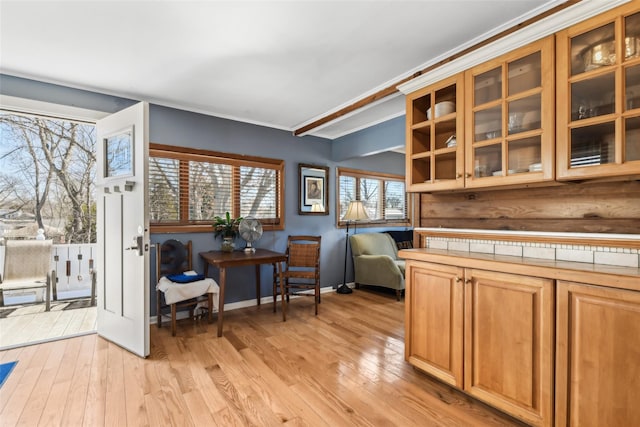 kitchen featuring tile counters, light wood-style flooring, glass insert cabinets, and baseboards