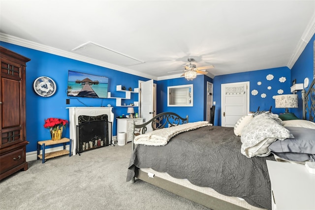 carpeted bedroom featuring ceiling fan, attic access, a fireplace, and ornamental molding