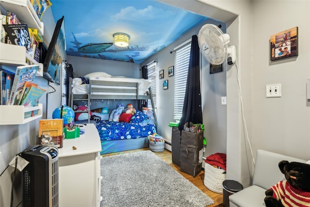 bedroom featuring a baseboard heating unit and wood finished floors