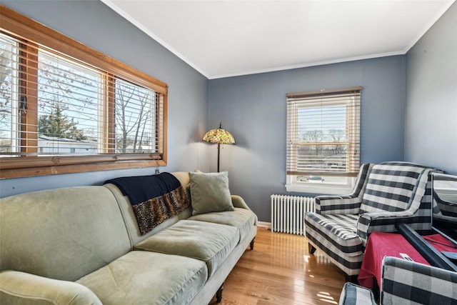 living area with radiator heating unit, wood finished floors, baseboards, and ornamental molding