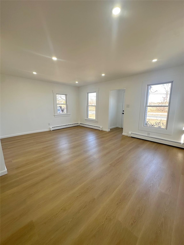 unfurnished room with a baseboard heating unit, recessed lighting, and wood finished floors