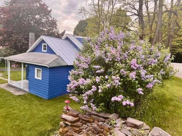 view of side of home with a lawn and a chimney