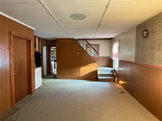 interior space with a wainscoted wall, stairway, visible vents, and wood walls