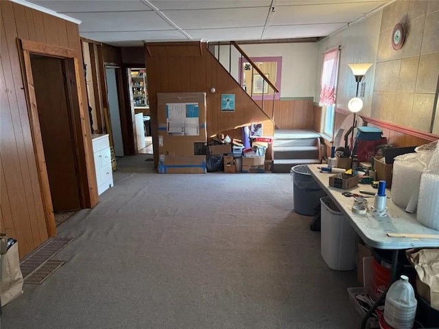 misc room with stairway, a paneled ceiling, wood walls, and carpet floors