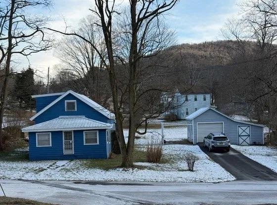 exterior space with an outbuilding, driveway, metal roof, and a detached garage