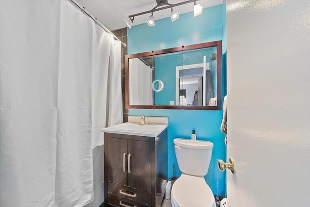 full bathroom featuring rail lighting, toilet, and vanity