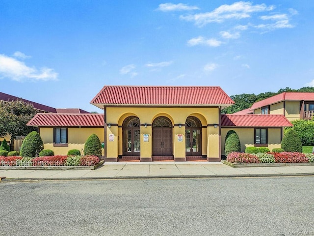 mediterranean / spanish home with a tile roof, french doors, and stucco siding