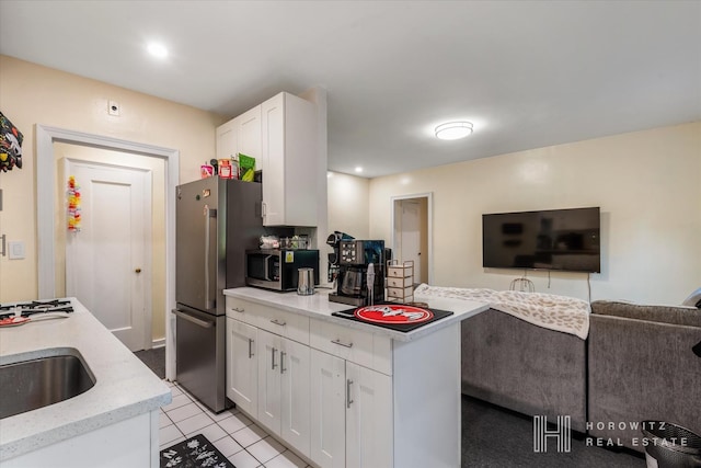 kitchen with light stone countertops, open floor plan, appliances with stainless steel finishes, white cabinets, and a sink