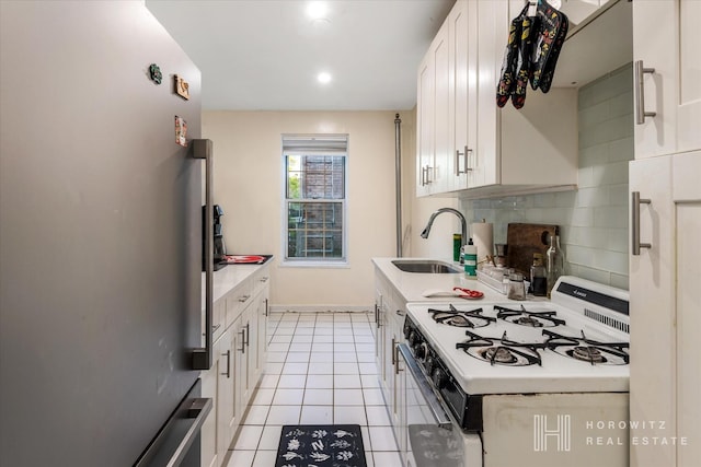 kitchen with white range with gas cooktop, a sink, tasteful backsplash, fridge, and light tile patterned floors