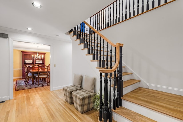 stairway featuring wood finished floors, baseboards, recessed lighting, crown molding, and a chandelier