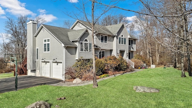 view of side of property with a chimney, aphalt driveway, a garage, a yard, and a shingled roof