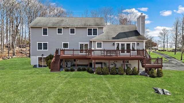back of house featuring a chimney, a lawn, a deck, and stairs