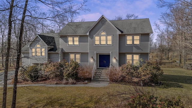view of front of property with a shingled roof and a front lawn