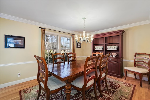 dining room with ornamental molding, baseboards, an inviting chandelier, and light wood-style floors