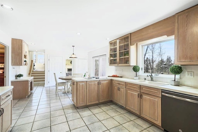 kitchen with light tile patterned floors, a sink, a peninsula, backsplash, and stainless steel dishwasher