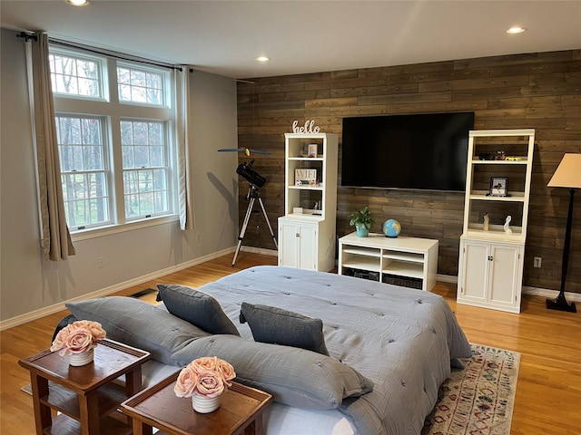 bedroom with wooden walls, light wood-type flooring, baseboards, and recessed lighting