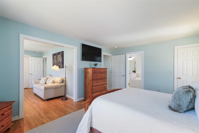 bedroom featuring light wood-style flooring, baseboards, and ensuite bathroom