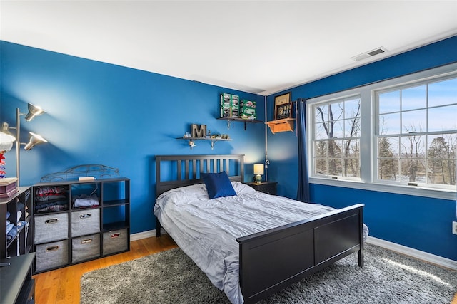 bedroom featuring wood finished floors, baseboards, and visible vents