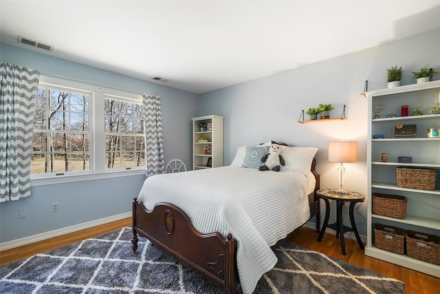 bedroom featuring wood finished floors, baseboards, and visible vents