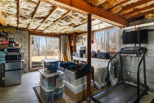 interior space with concrete block wall, fridge, and a toaster