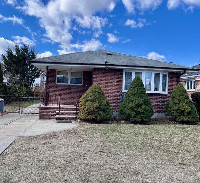 view of front of home featuring concrete driveway, a gate, fence, and brick siding