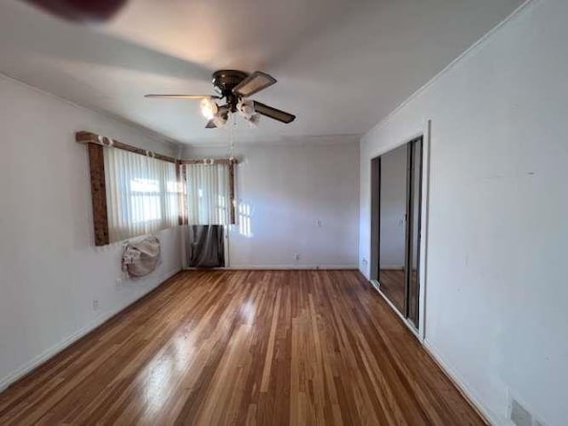 unfurnished bedroom featuring visible vents, baseboards, ceiling fan, and wood finished floors