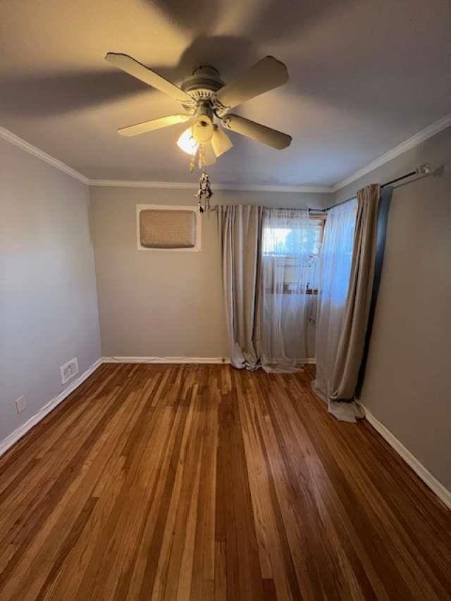 unfurnished bedroom with ceiling fan, crown molding, baseboards, and wood finished floors