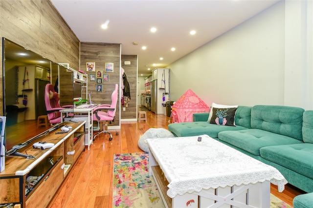 living area featuring recessed lighting, stairway, light wood-style flooring, and wood walls