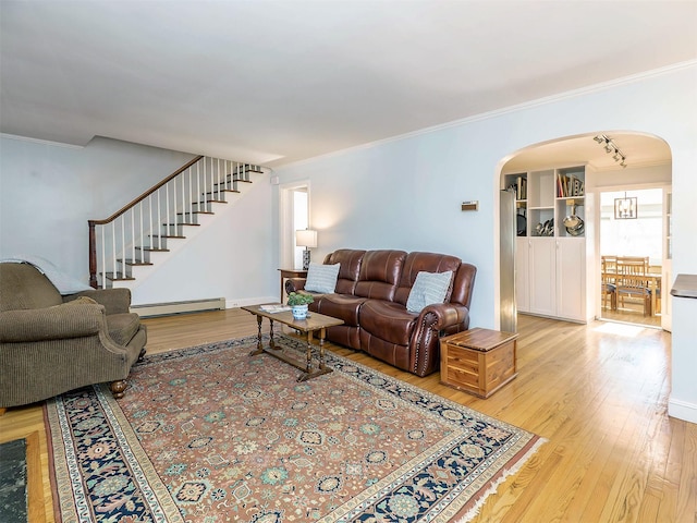 living room with light wood-type flooring, ornamental molding, stairway, arched walkways, and baseboard heating