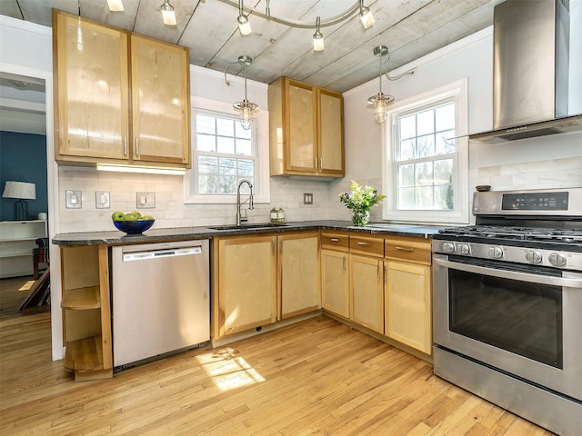 kitchen featuring light brown cabinetry, wall chimney exhaust hood, appliances with stainless steel finishes, and a sink