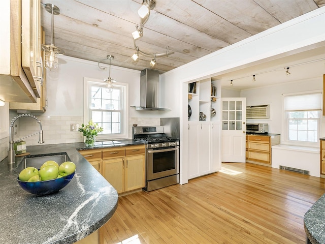 kitchen with visible vents, a sink, dark countertops, gas stove, and wall chimney exhaust hood