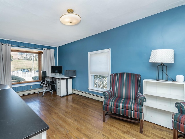 office space featuring a baseboard heating unit and wood finished floors