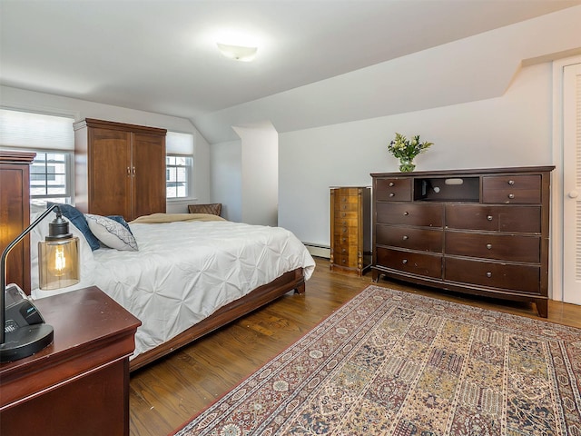 bedroom with a baseboard radiator, lofted ceiling, and wood finished floors