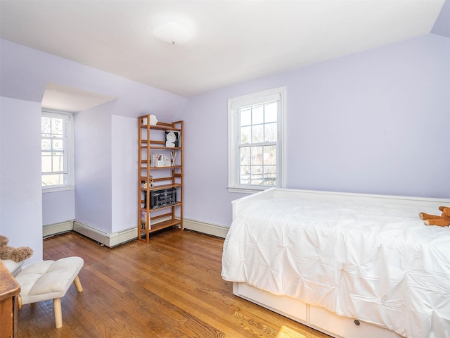 bedroom with multiple windows, lofted ceiling, baseboard heating, and wood finished floors