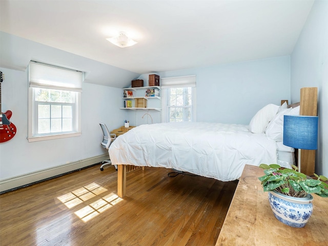 bedroom featuring vaulted ceiling, multiple windows, wood finished floors, and a baseboard radiator