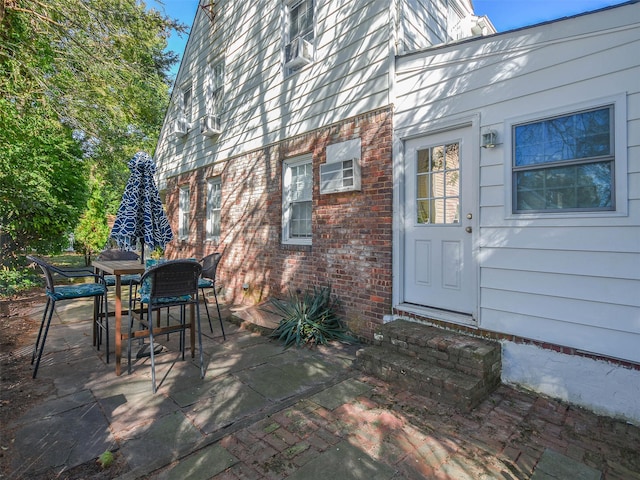 property entrance featuring brick siding, outdoor dining area, and a patio