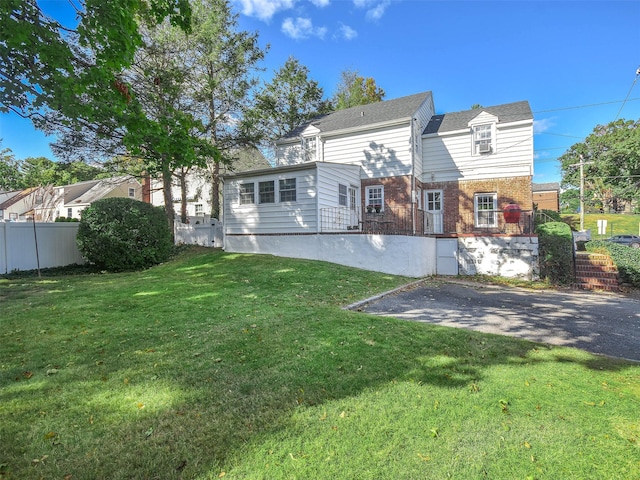 rear view of property featuring a yard, brick siding, and fence