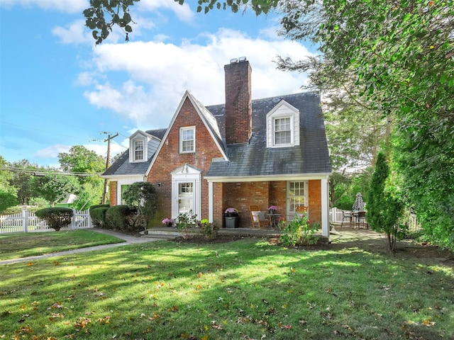 view of front of house featuring brick siding, a front lawn, and fence