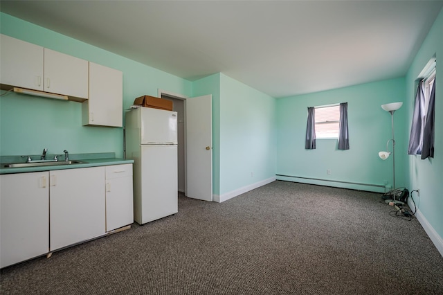 kitchen featuring a sink, a baseboard heating unit, dark carpet, freestanding refrigerator, and white cabinets