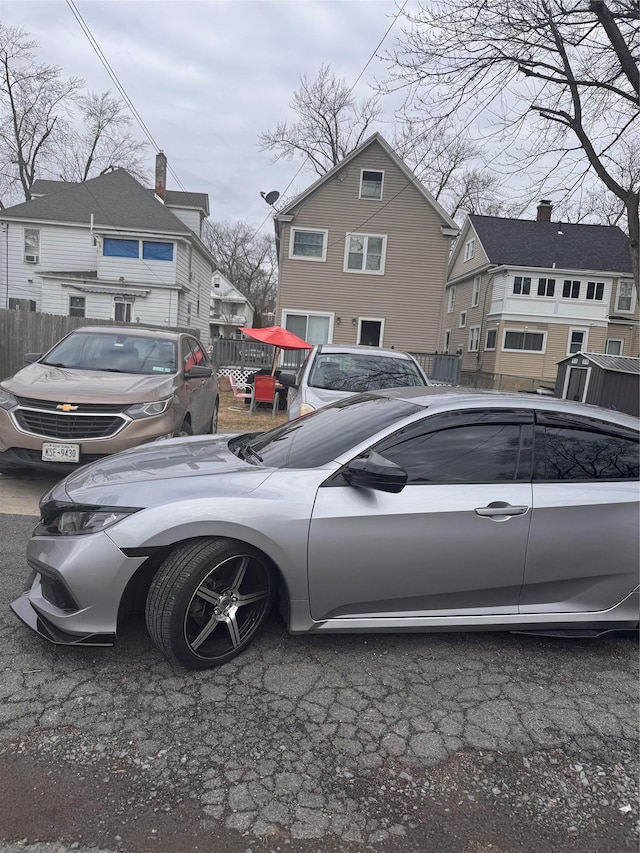 view of parking featuring a residential view and fence