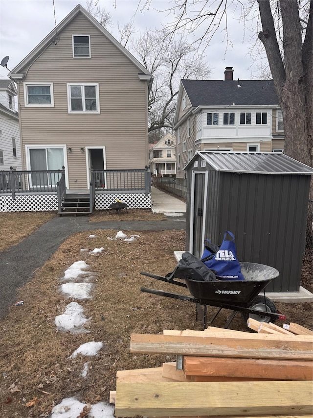 rear view of house with a storage unit, a wooden deck, and an outdoor structure